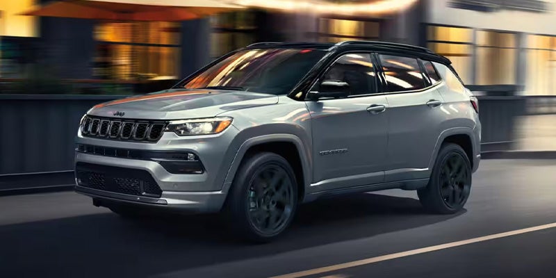 A silver Jeep Compass running on the road at night