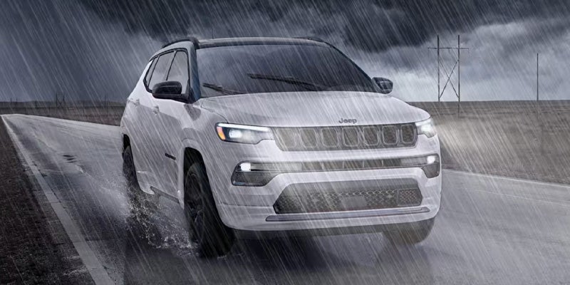 White Jeep Compass running on the road in heavy rain