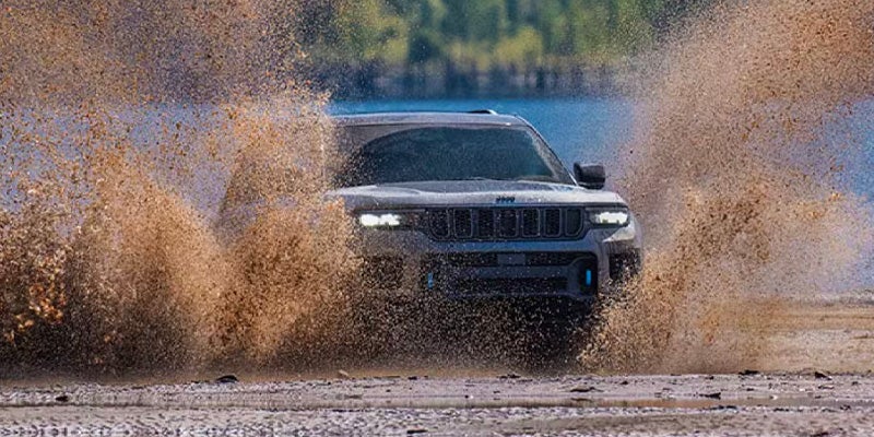 Jeep SUV splashing through muddy water at speed