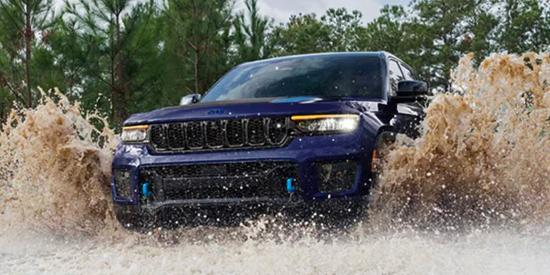 Blue Jeep Grand Cherokee L running in water side