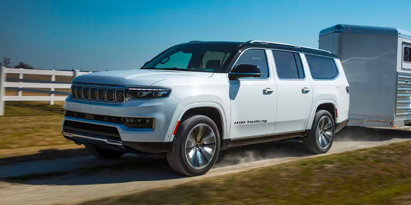 White 2025 Jeep Grand Wagoneer running offroading towing at back