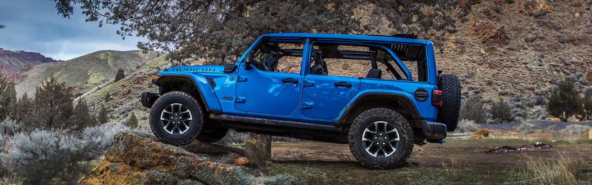 Blue 2025 Jeep Wrangler running off-roading in mountain area
