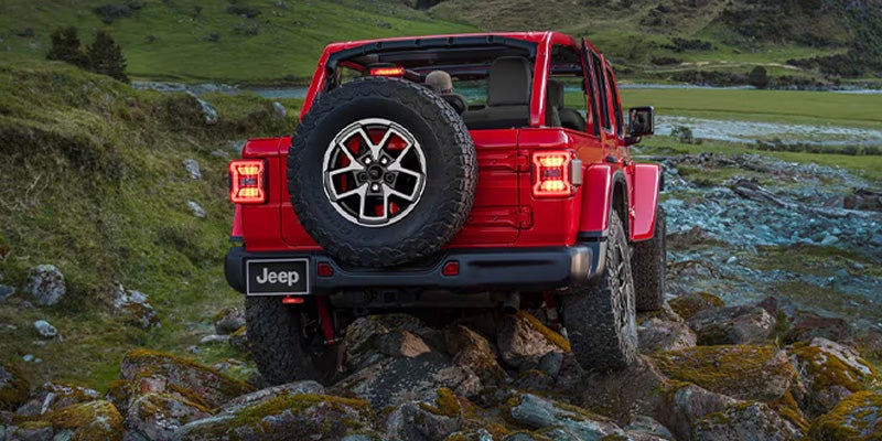 Red Jeep Wrangler running offroading in mountain area
